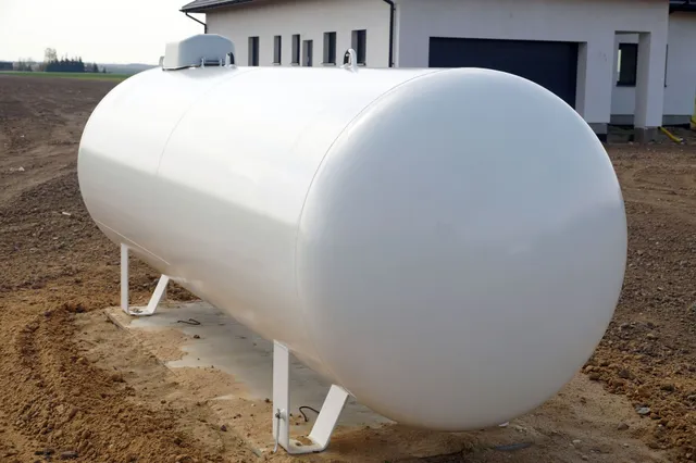 all white propane tank in a dirt field in front of a building