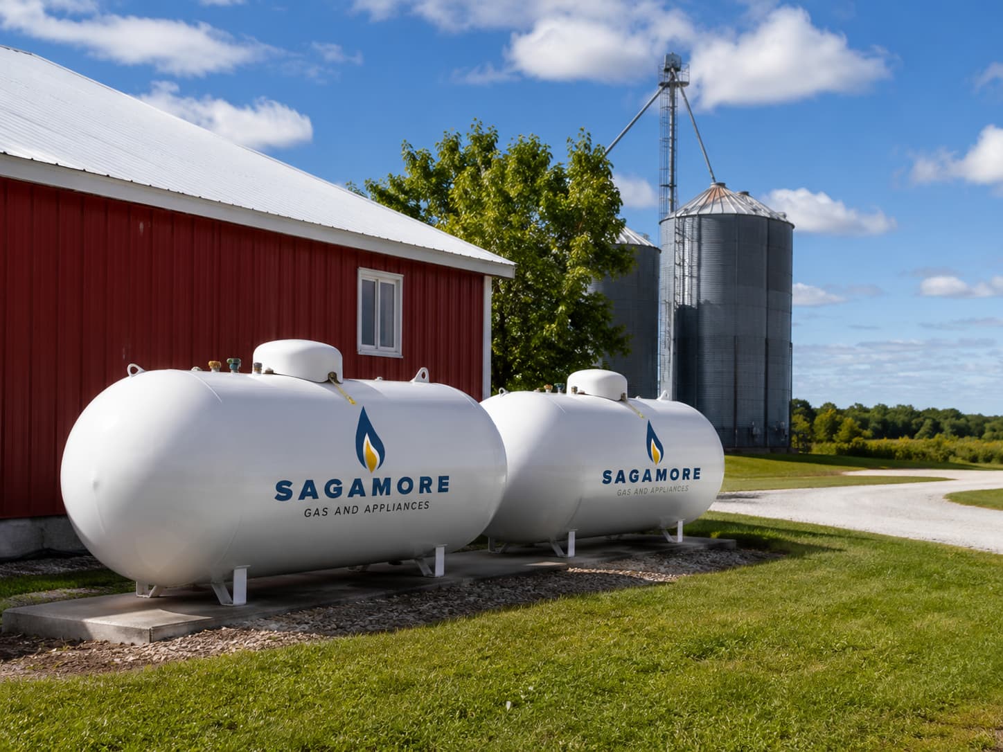 Two propane tanks labeled Sagamore Gas and Appliances beside a red barn and a grain silo on a sunny day.